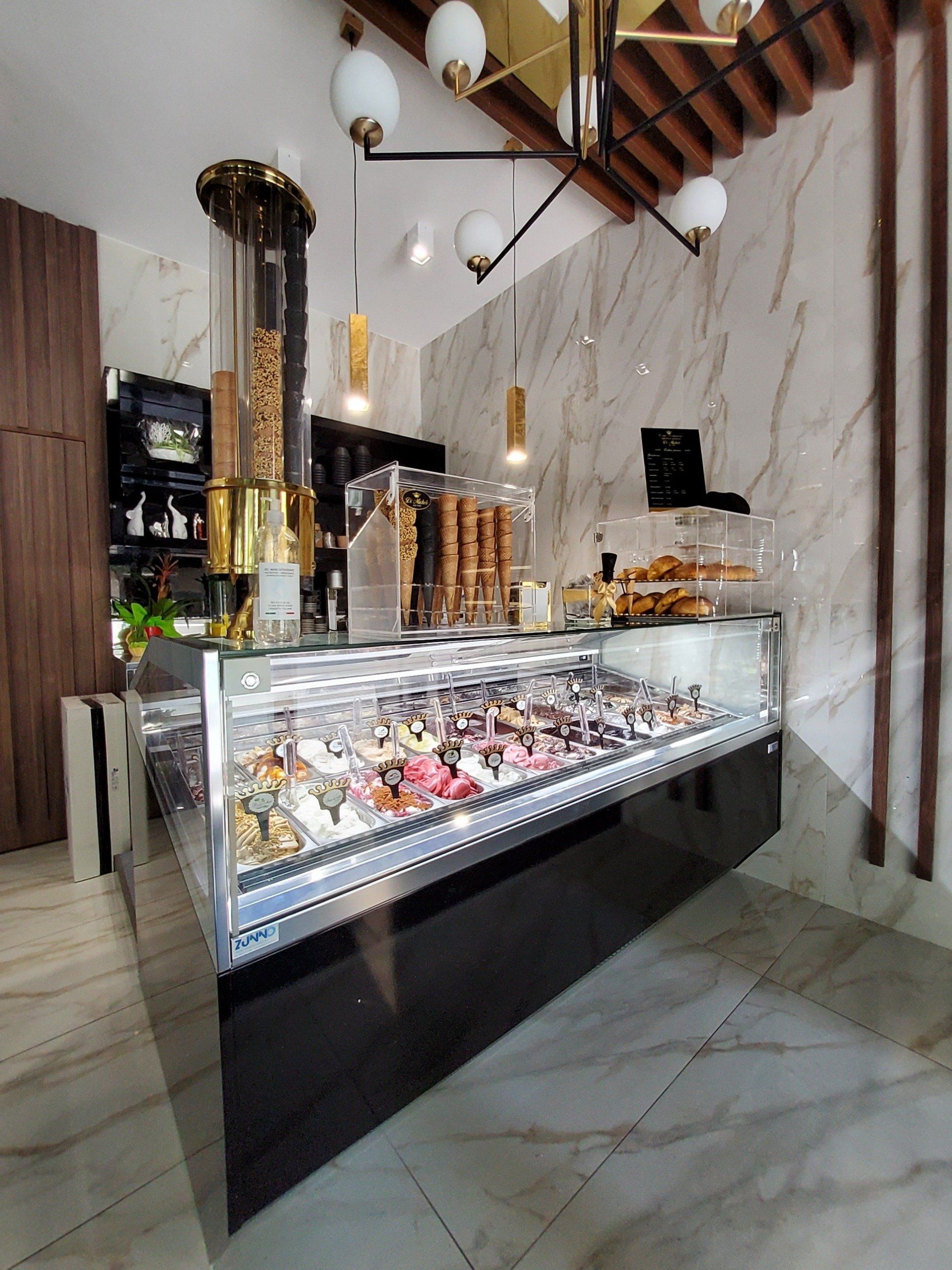 Gelateria con vetrina per i gelati, pareti in marmo e illuminazione moderna.
