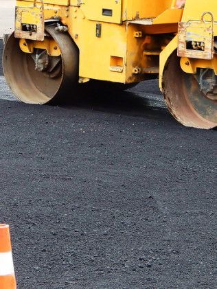 Yellow road roller paving dark asphalt on a construction site