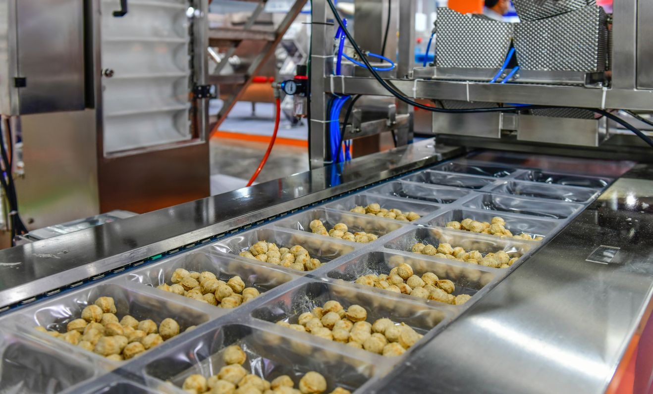 Bottling machine in a factory setting, filling glass bottles with liquid.