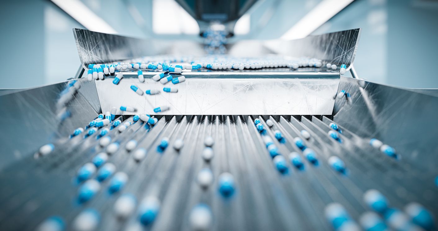 Cookies on a conveyor belt exiting an industrial oven in a factory.