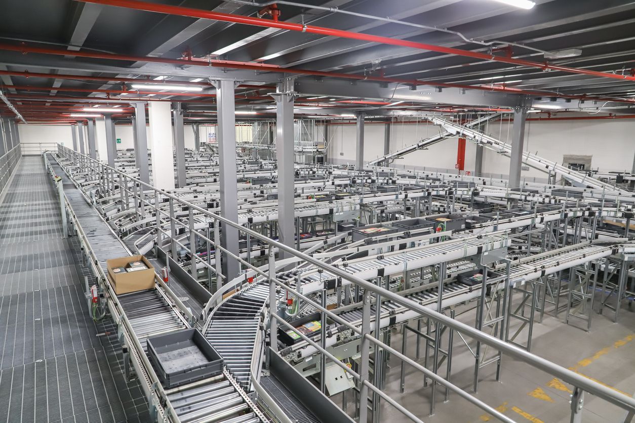 Large industrial warehouse with a complex network of conveyor belts and metal racks under bright overhead lights