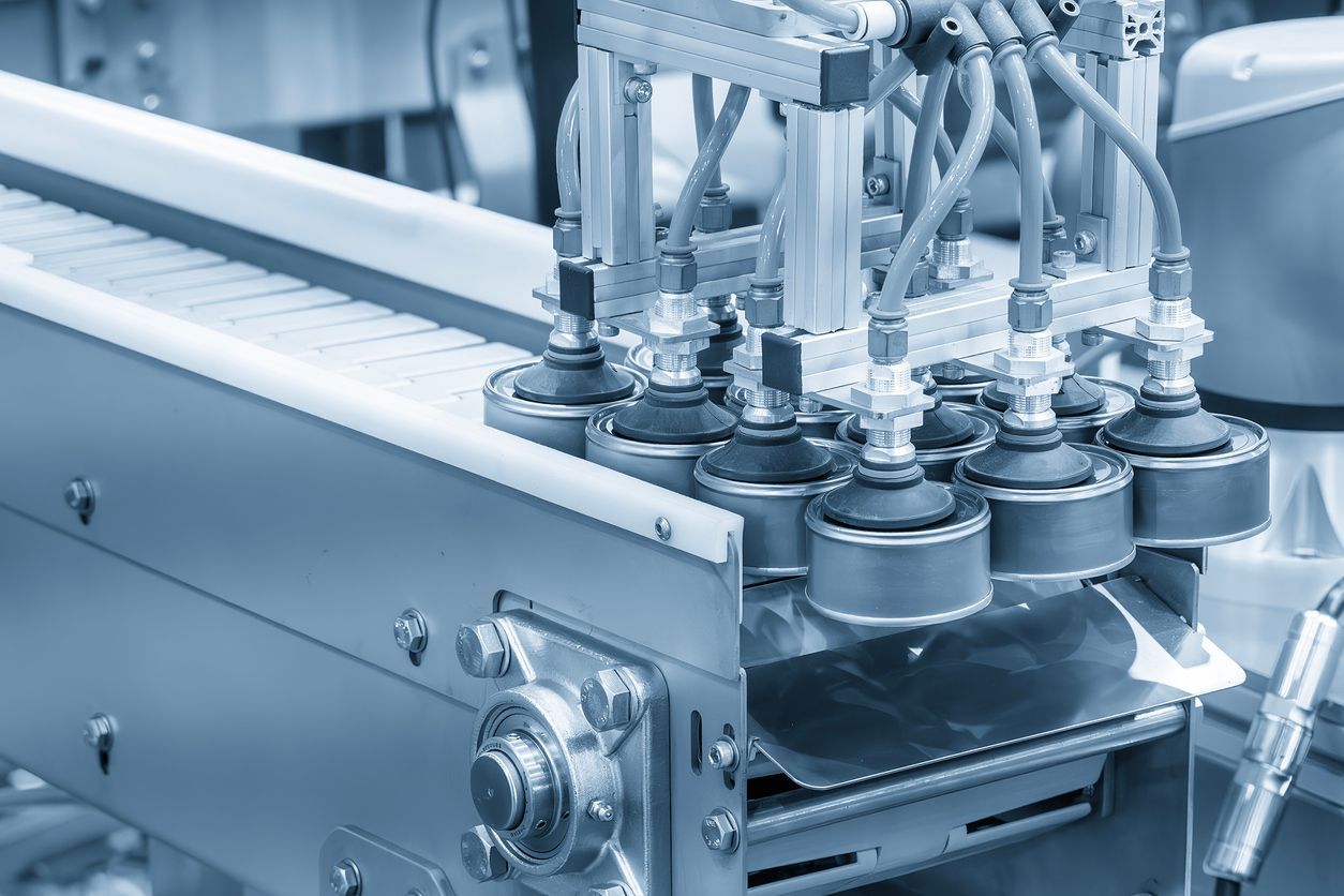 Industrial conveyor belt system with robotic suction nozzles in a factory setting.