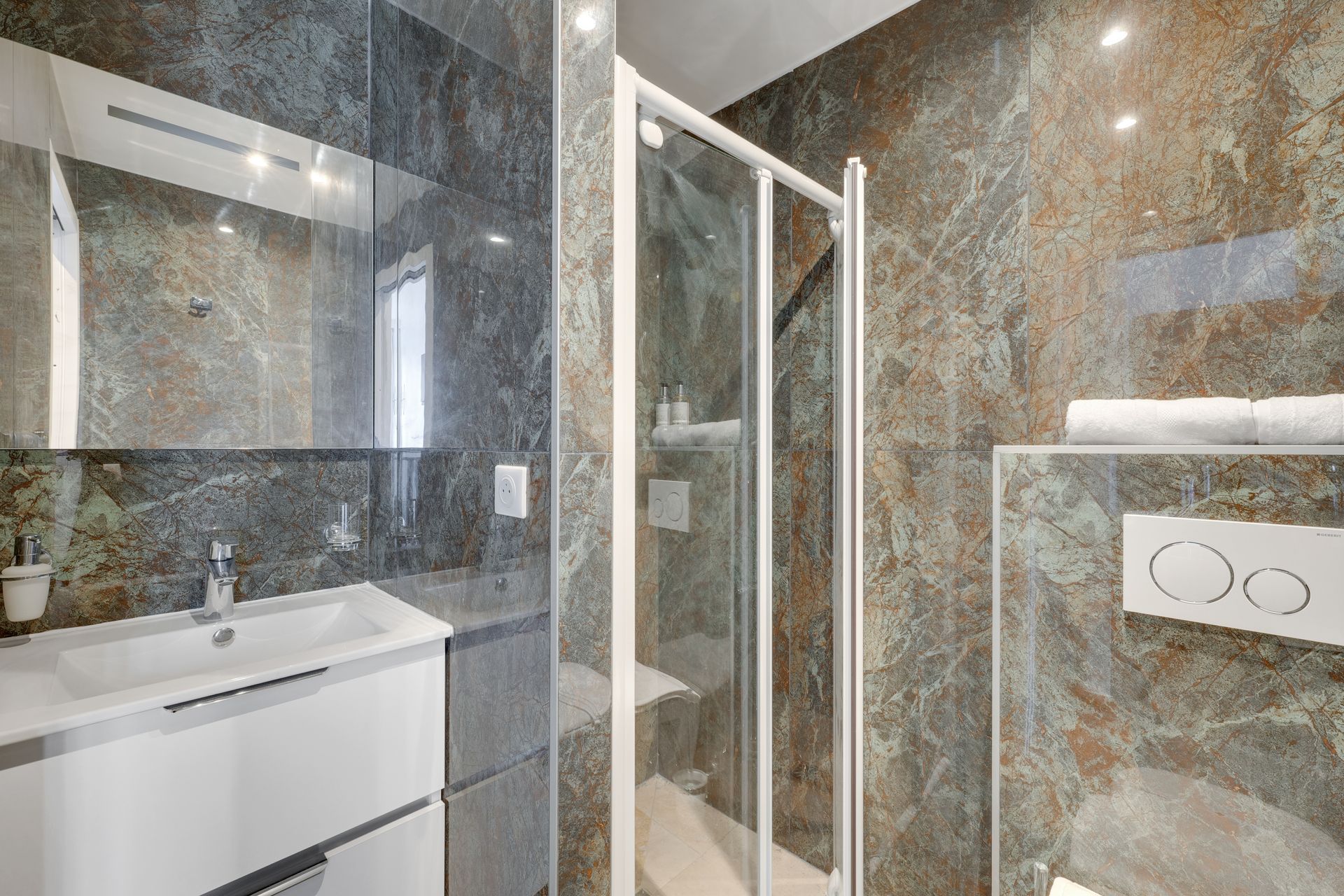 Modern bathroom with marble-look walls, a white sink cabinet, glass shower, and a large mirror.