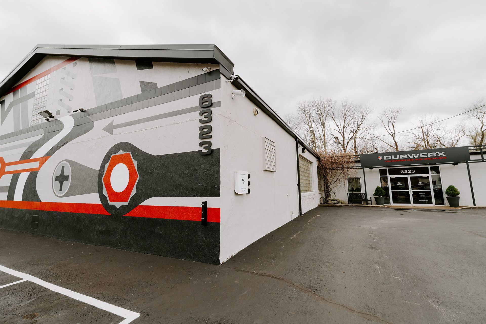 Graffiti-covered building beside a parking lot on an overcast day, with a covered entrance at right