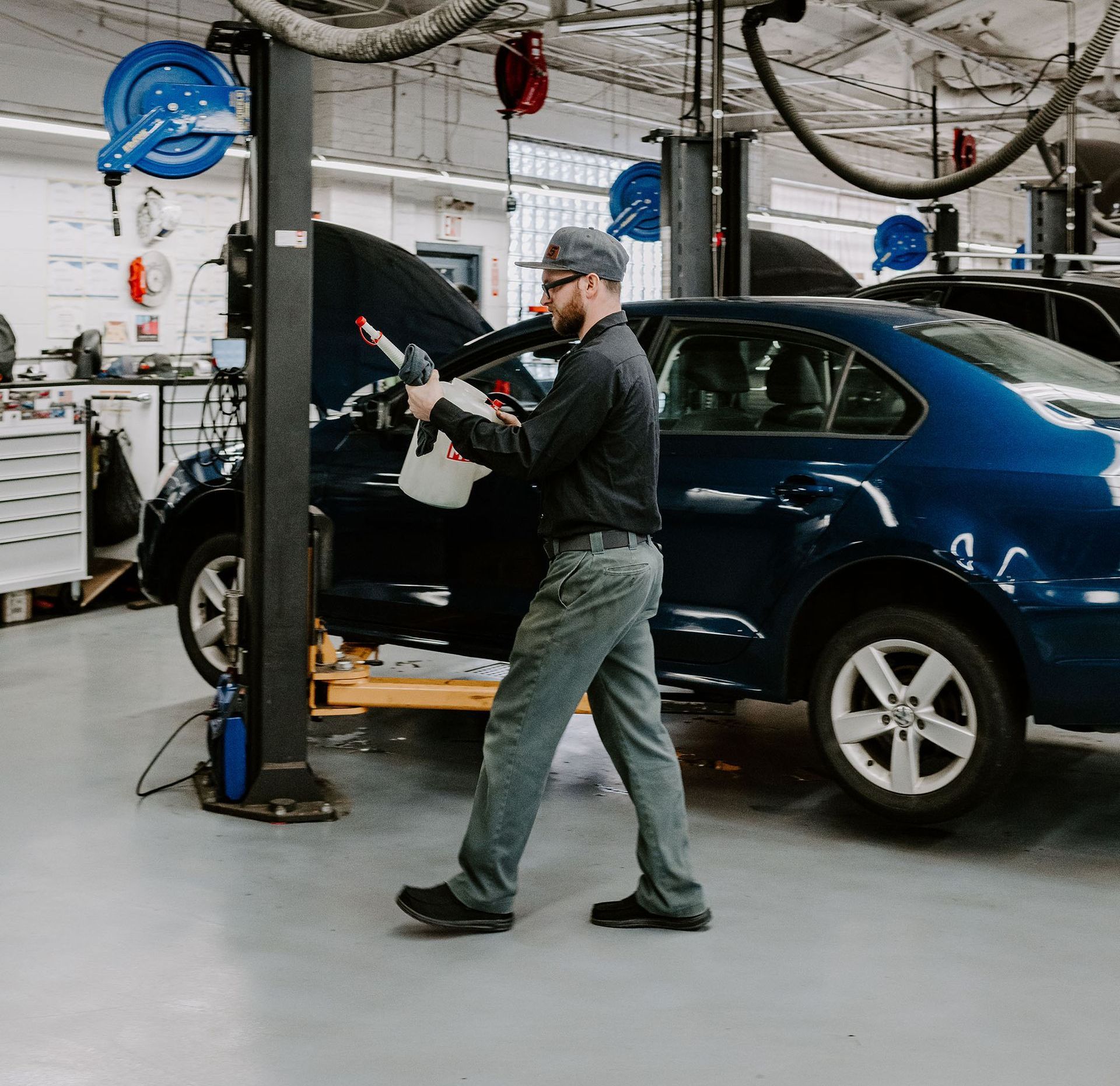 Mechanic working on a blue car in an auto repair shop with the hood open