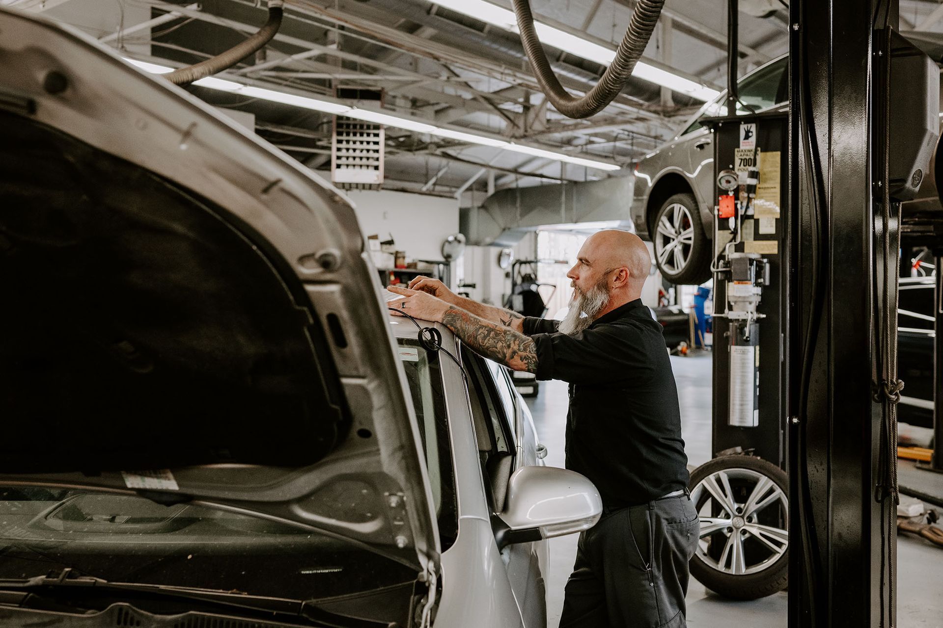 Mechanic working on a car in a repair garage with the hood open