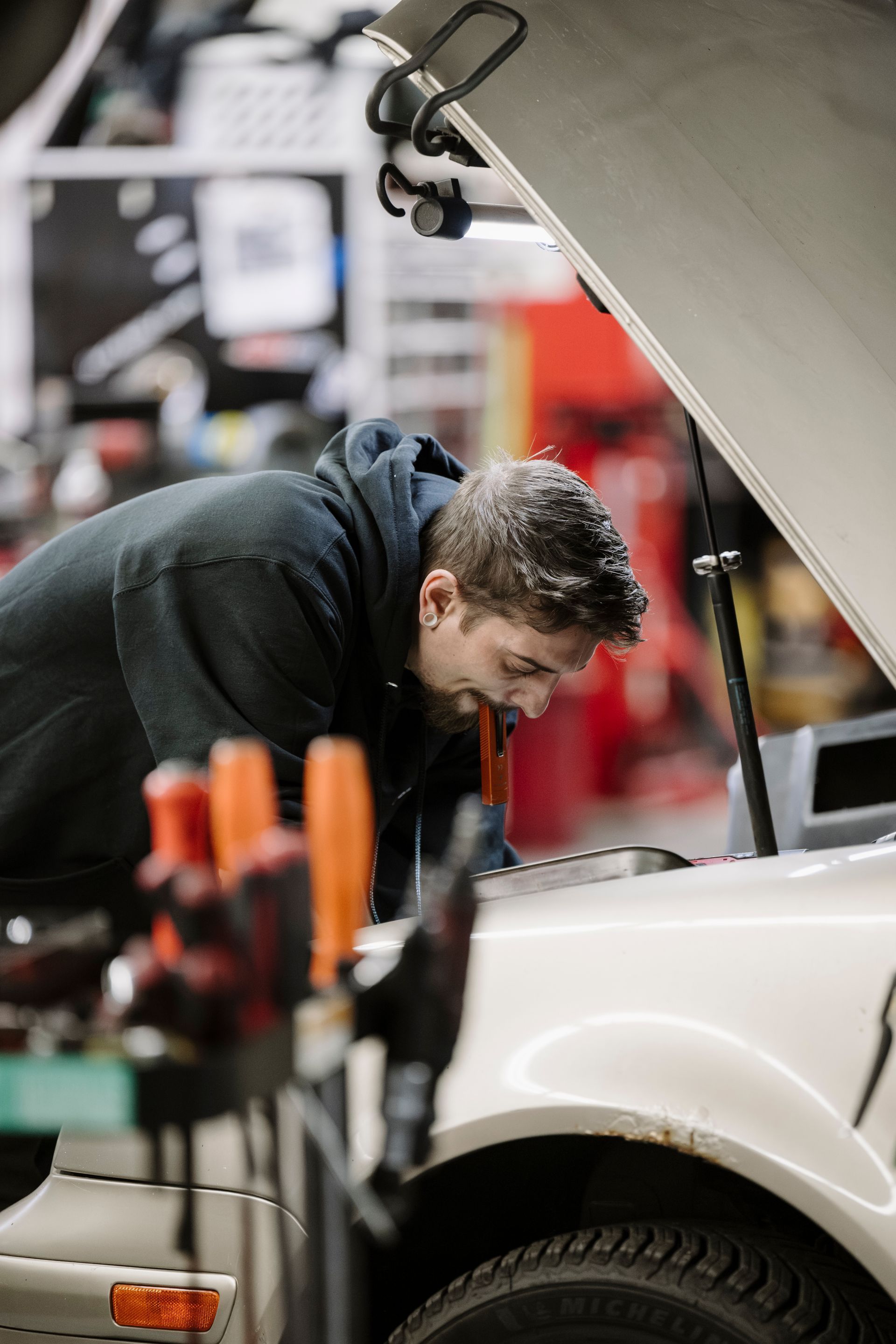 Mechanic inspecting a car engine with hood open in a garage
