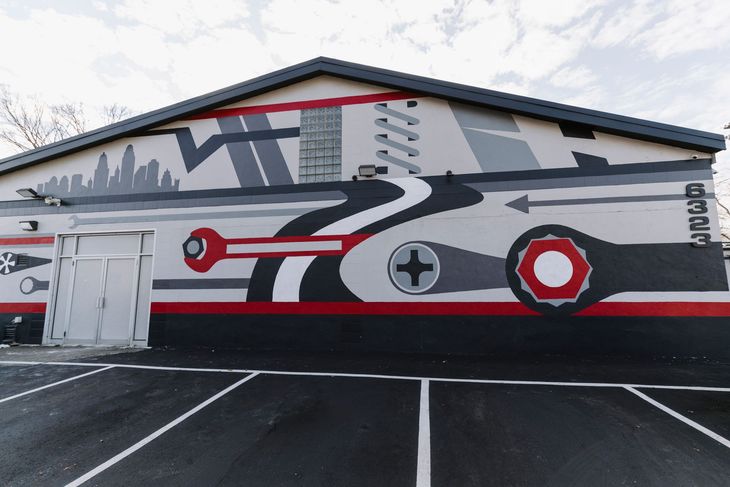 Mural of a gray fighter jet on a building wall with red, black, and white accents