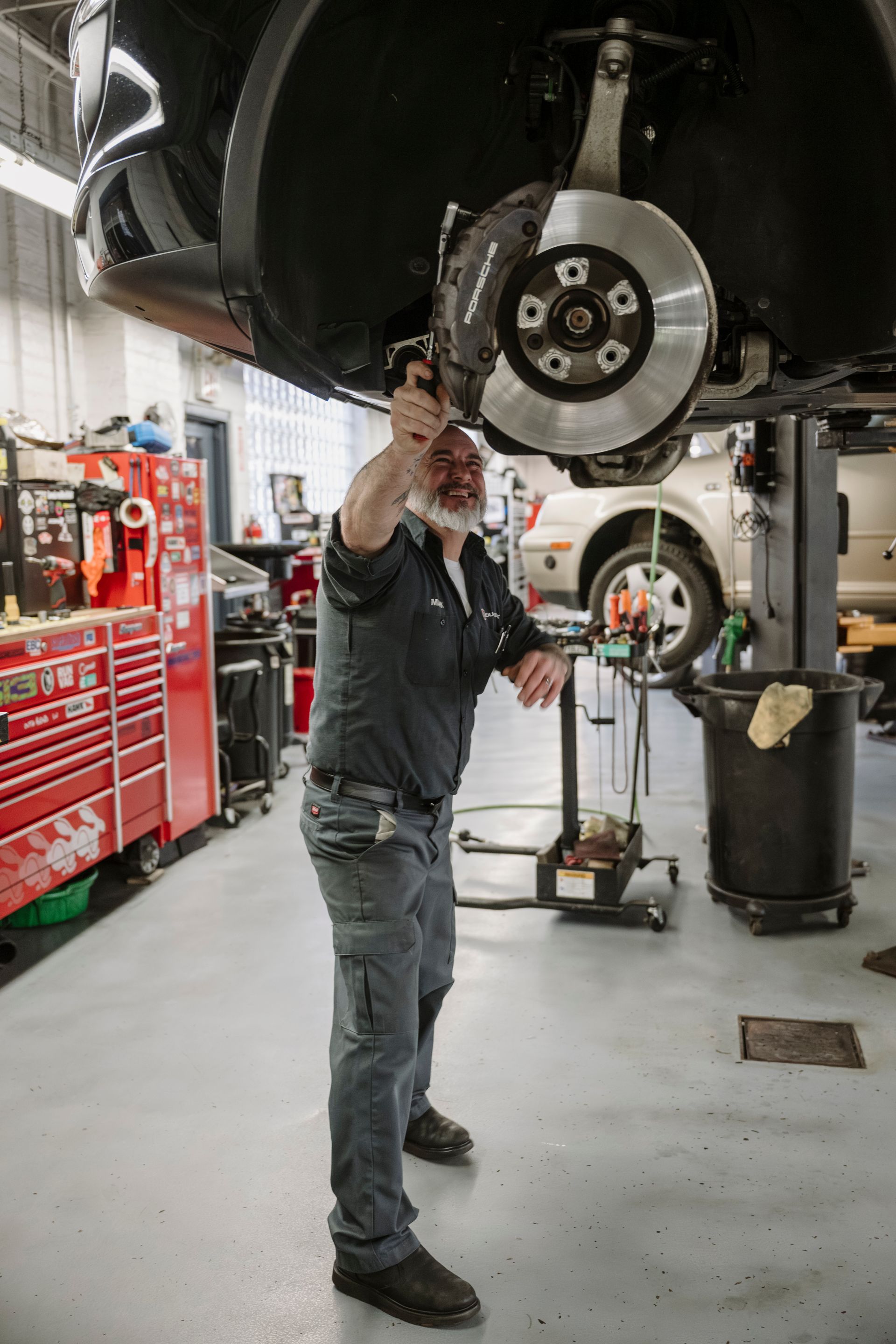 Mechanic inspecting a car’s wheel and brake assembly in an auto shop
