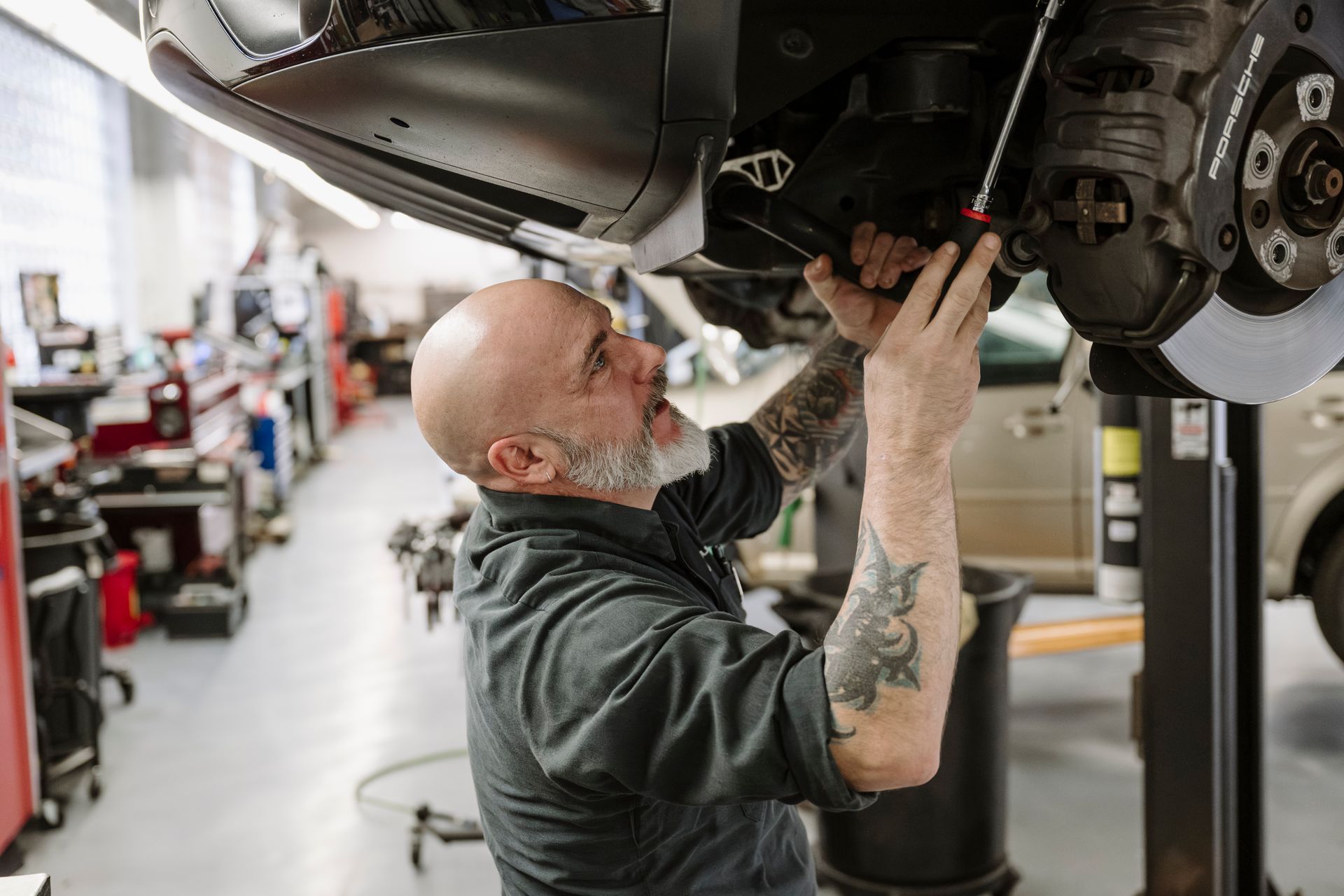 Mechanic working under a lifted car in an auto repair shop