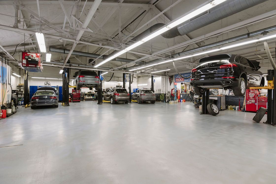 Auto repair shop with several cars on lifts in a bright garage