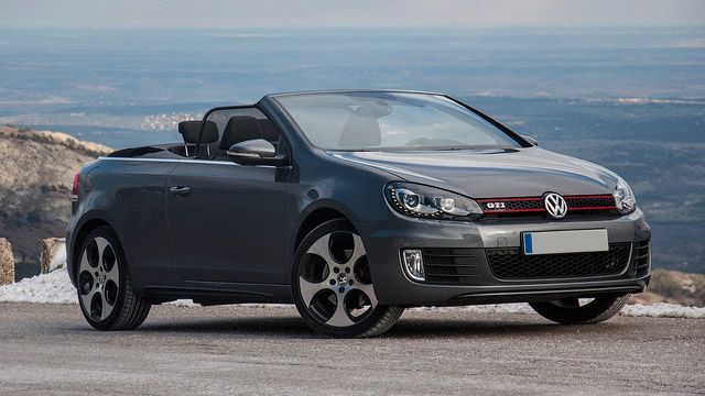 Dark gray Volkswagen convertible parked on a mountain overlook with ocean in the background