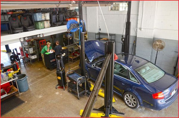 Blue car in an auto repair garage with a lift and mechanic tools nearby