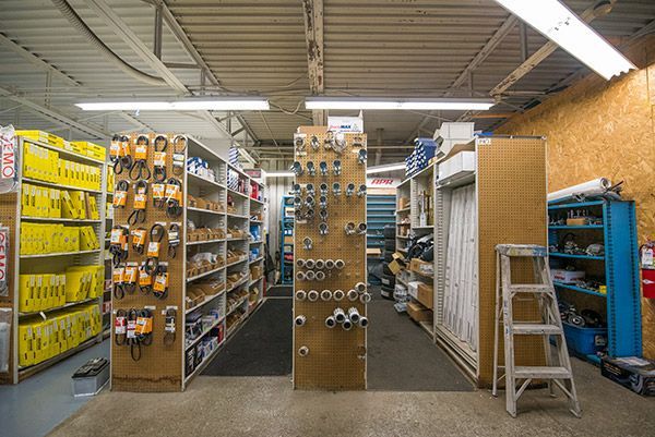 A storage aisle with shelves of packaged goods, a ladder, and warehouse lighting