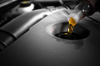 Close-up of oil being poured into a car engine through the oil filler opening