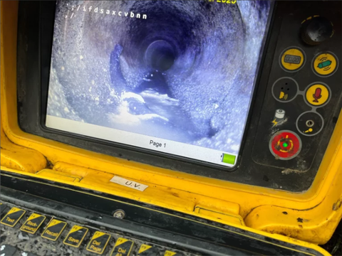 Yellow inspection monitor showing a dark tunnel or pipe interior on screen, with control buttons on the right.
