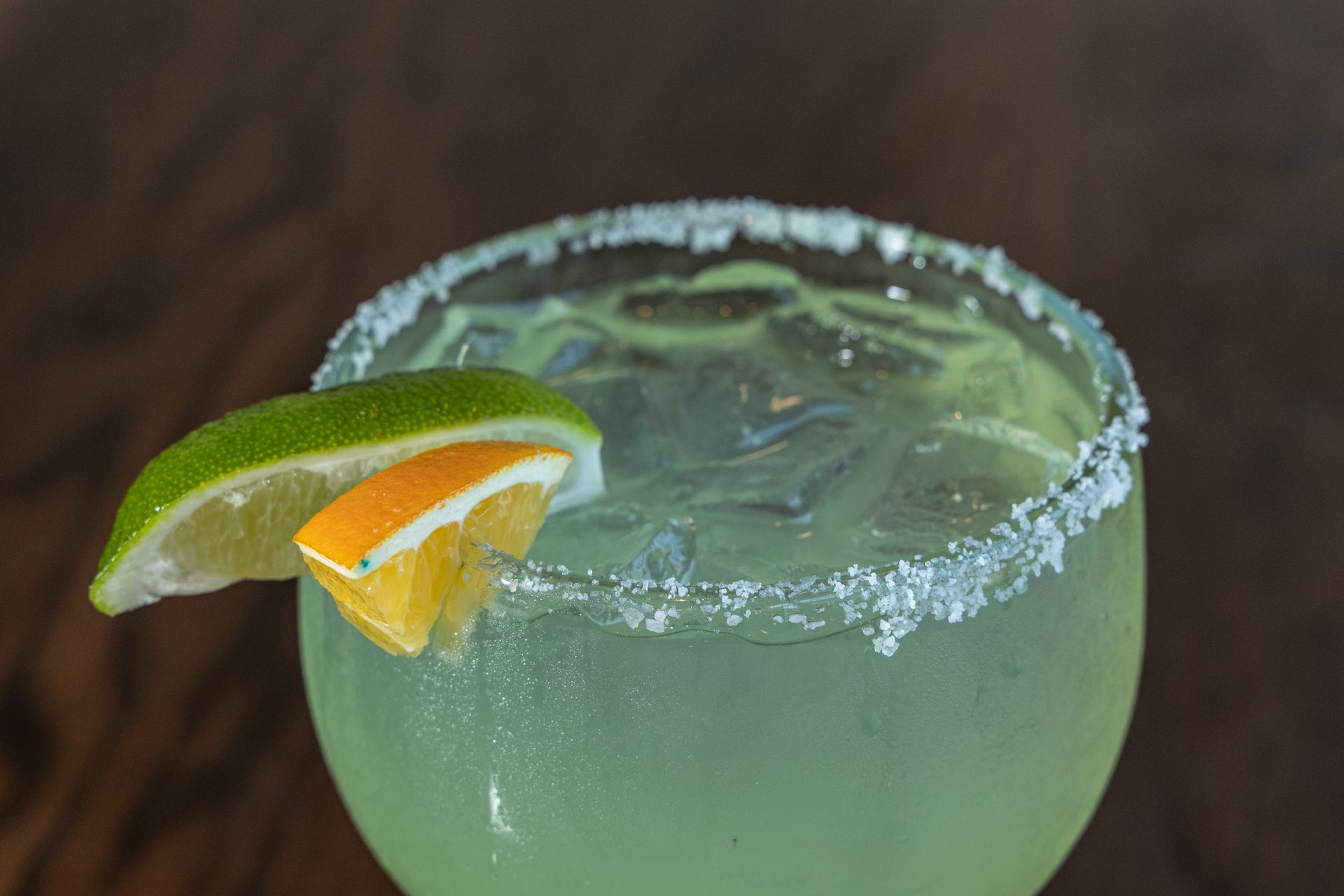 Margarita in a glass with salt rim, lime and orange garnish.