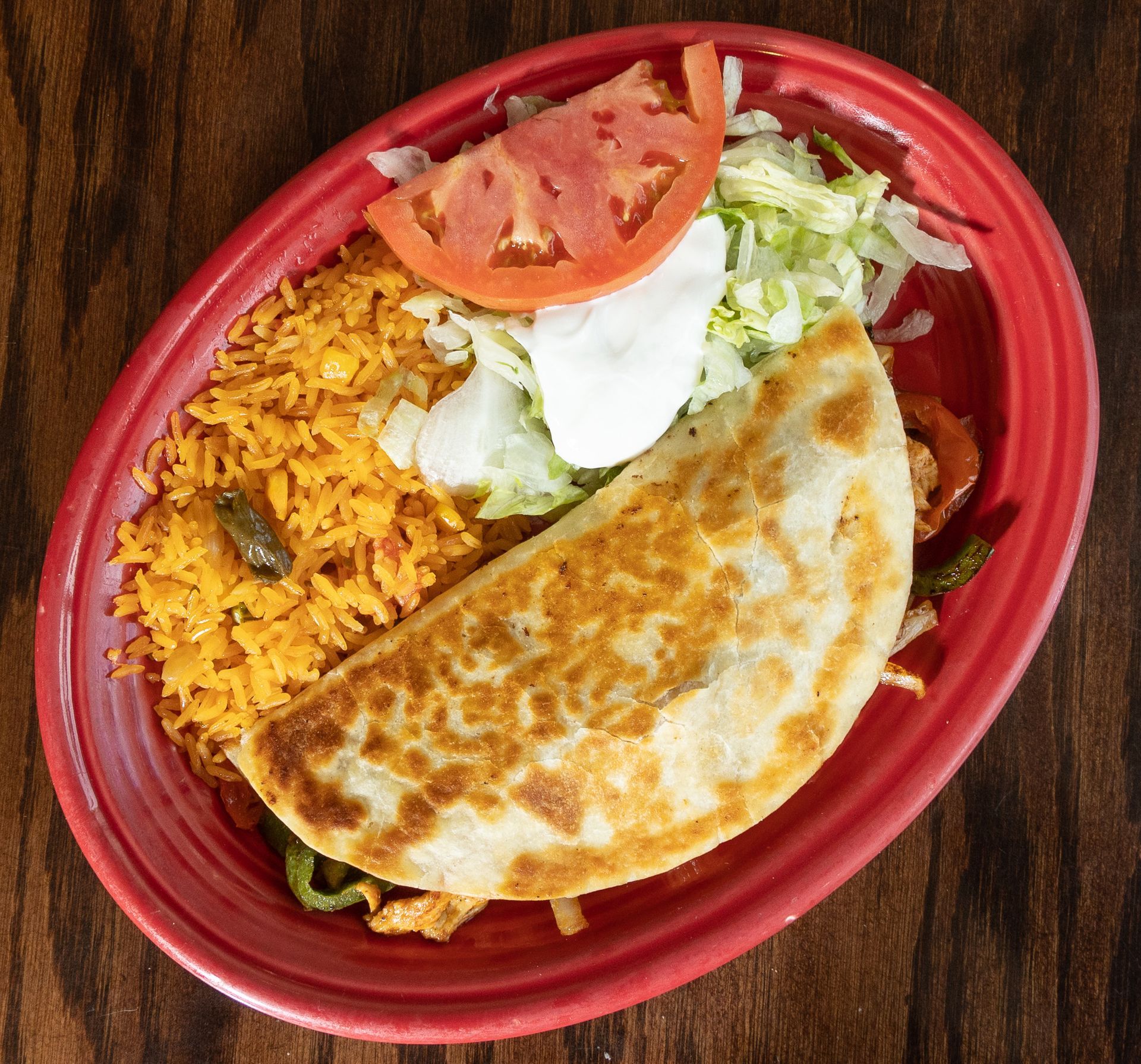 Quesadilla, rice, and toppings on red plate.