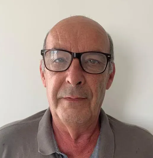 homem de oculos olhando para a camera e fundo branco atrás 