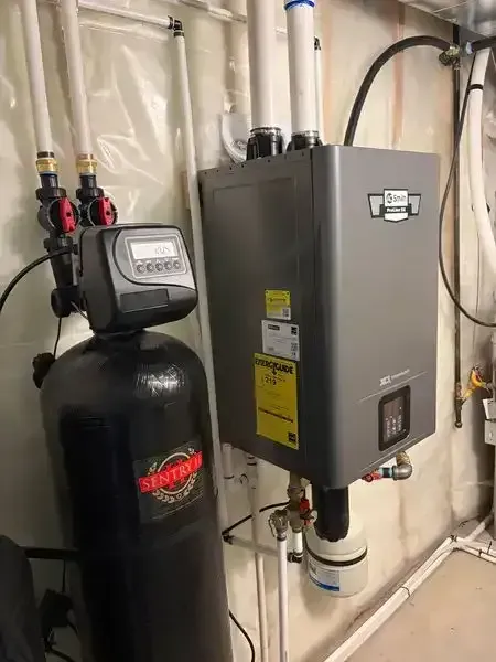 Water softener and gray HVAC control box in a basement with insulated walls and exposed pipes. Water softener and gray HVAC control box in a basement with insulated walls and exposed pipes.