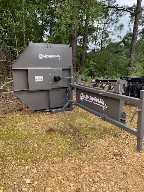 A large, gray Limenha wood chipper in a wooded area.