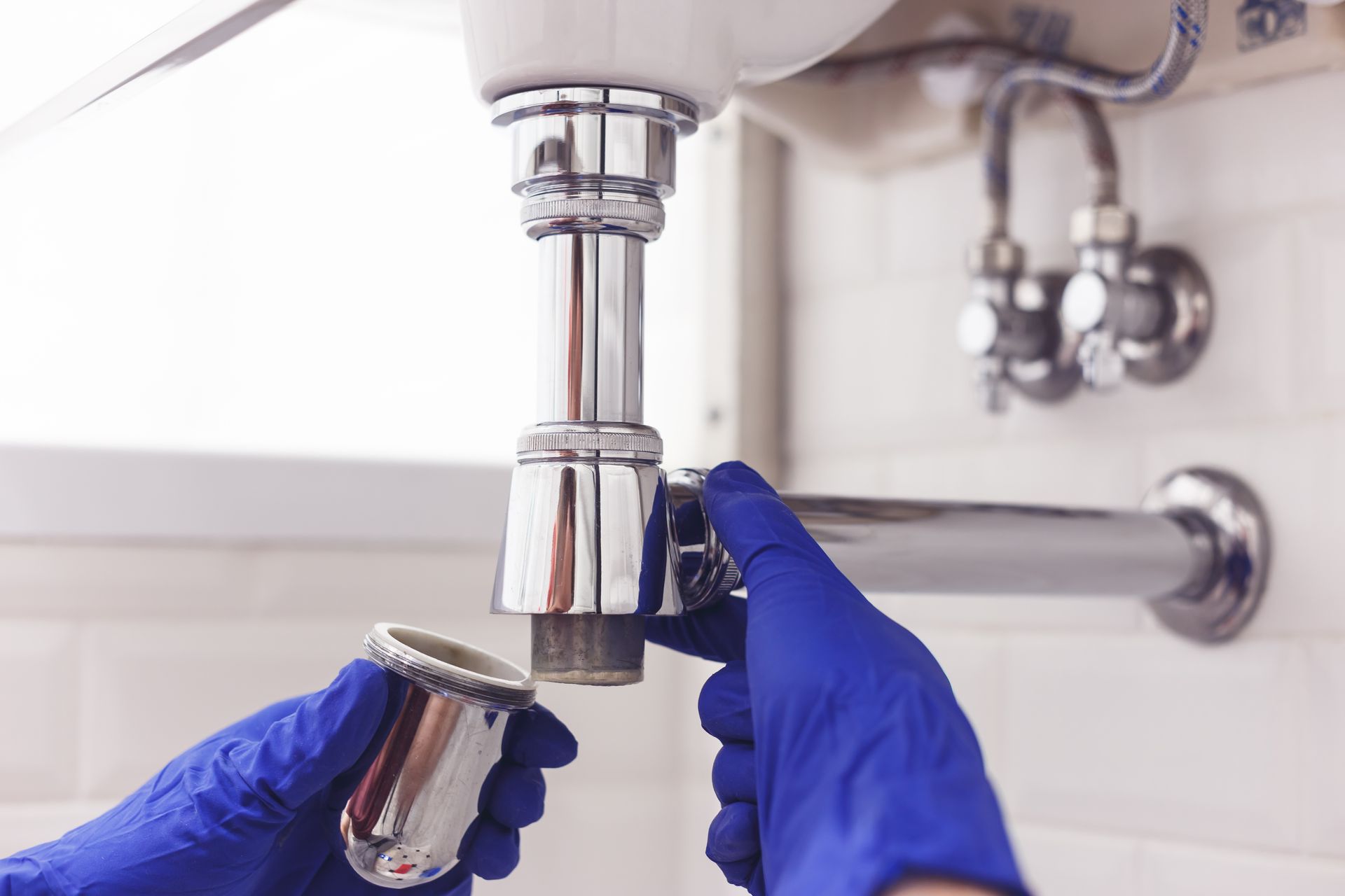 Plumber repairs and maintains chrome siphon.