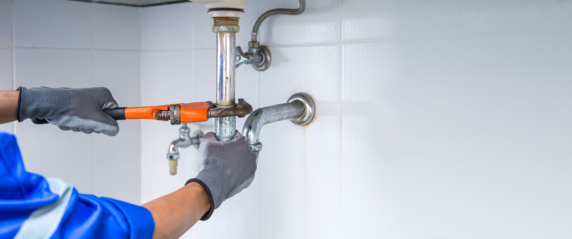 Technician plumber using a wrench to repair a water pipe.