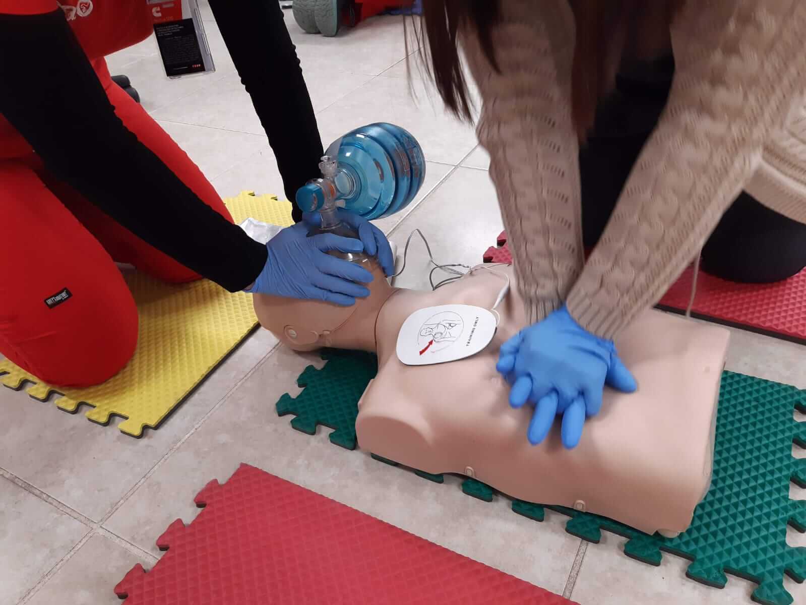 Dos personas realizando RCP en un maniquí durante una sesión de entrenamiento.