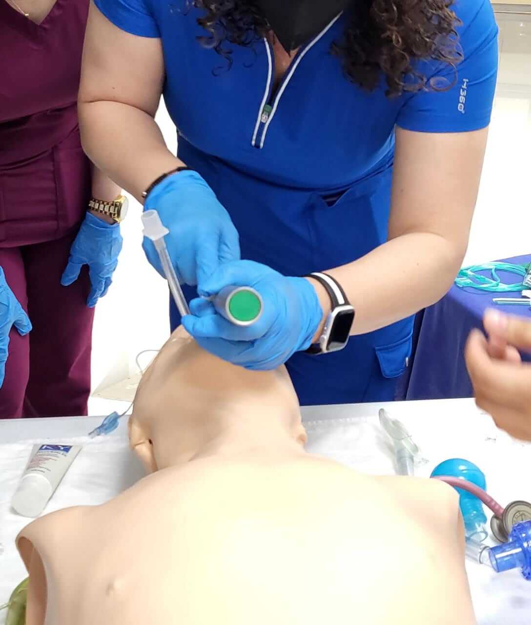 Persona con uniforme azul practicando la intubación en un maniquí.