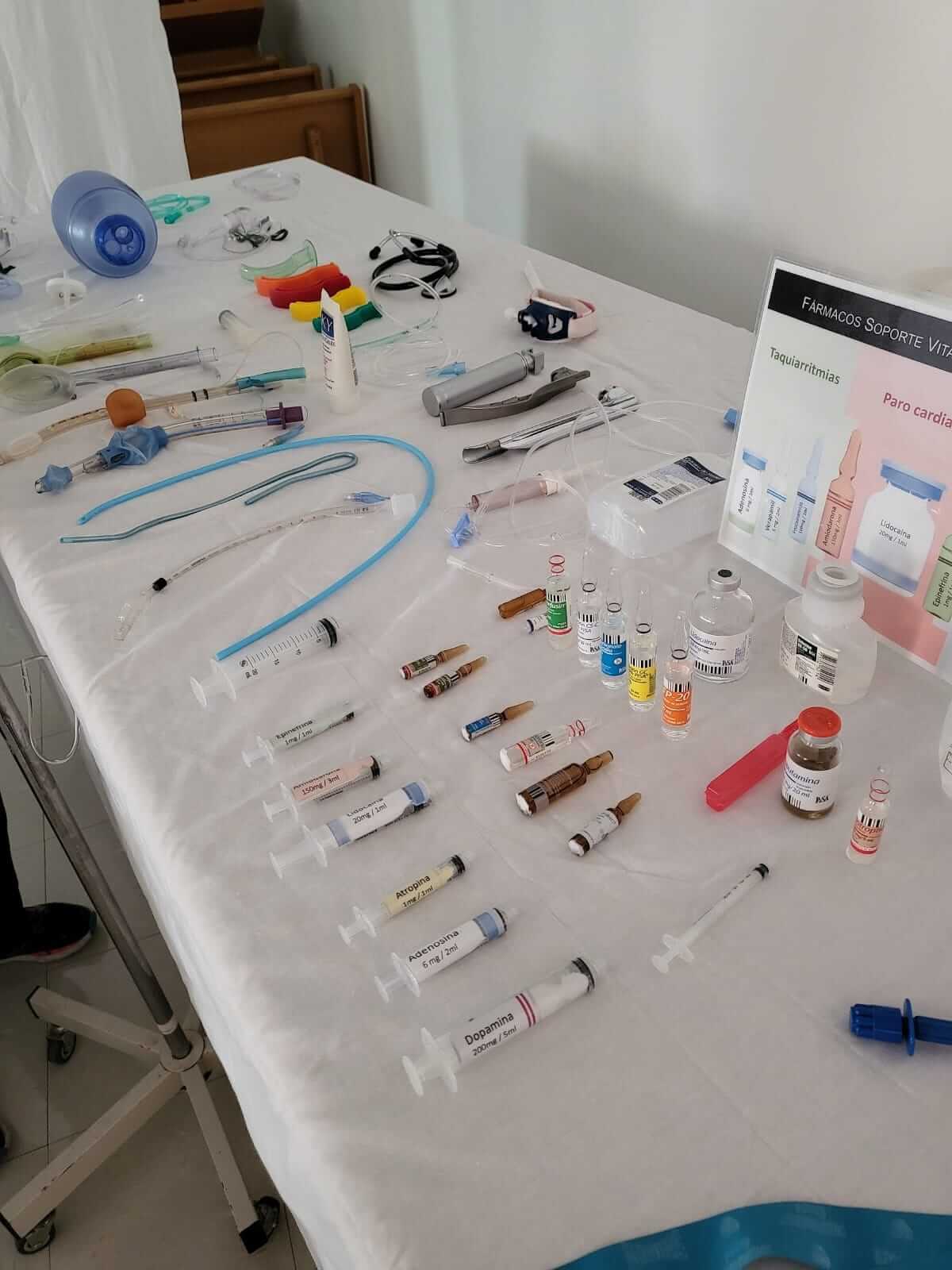 Mesa cubierta con suministros médicos: jeringas, viales, tubos y otros equipos.