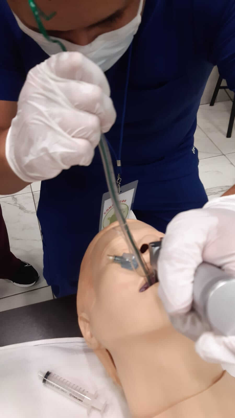Profesional médico intubando un maniquí, utilizando instrumentos y usando guantes.