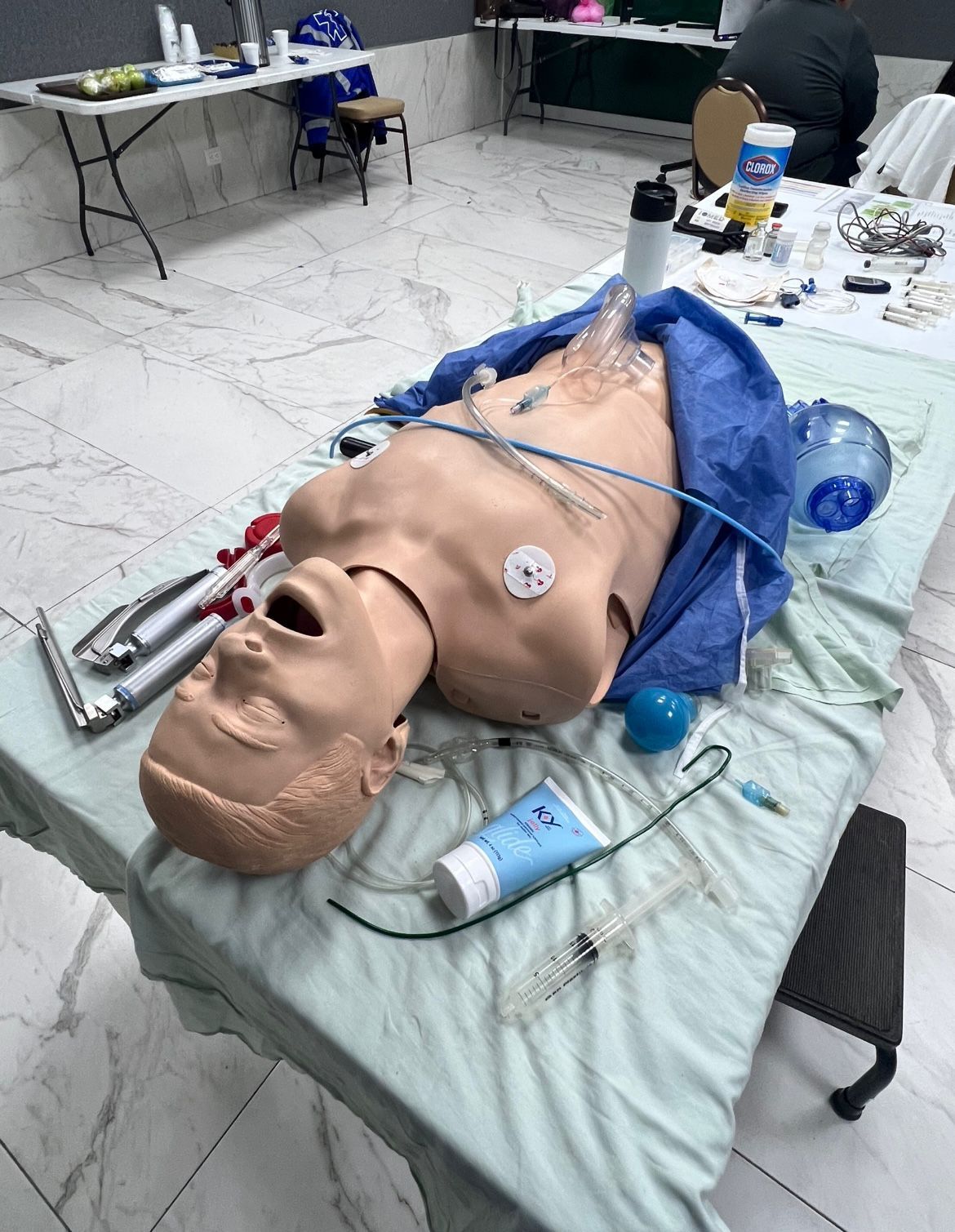 Maniquí sobre una mesa con suministros médicos, preparado para una simulación médica.