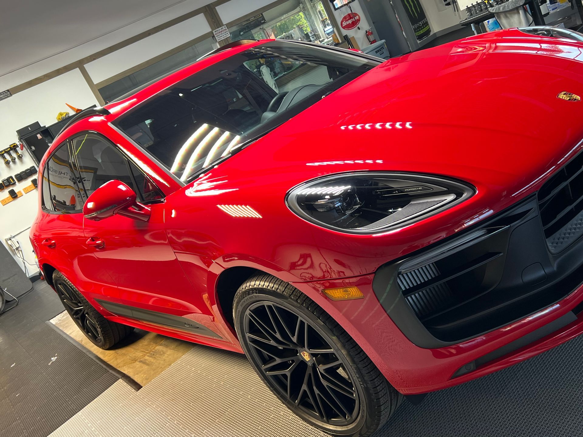 Red Porsche SUV with black wheels parked indoors.