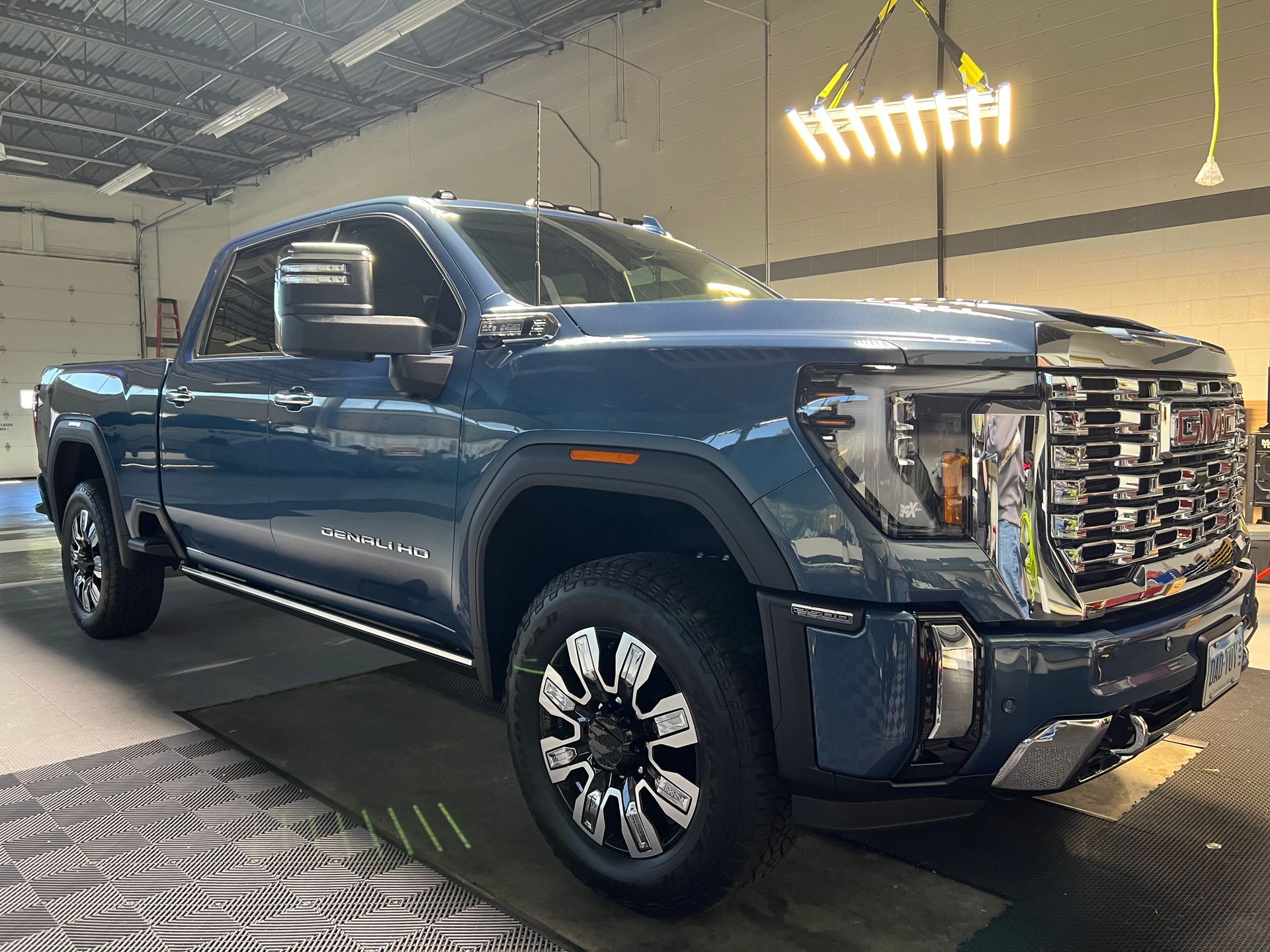 Blue GMC truck in a garage, angled front view, under lights.