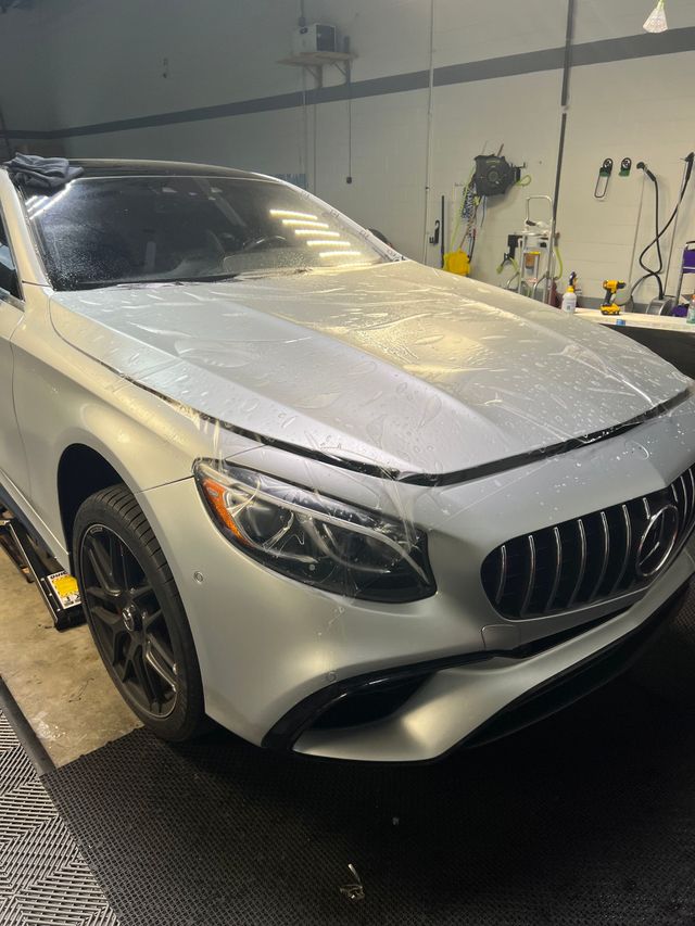 A car is being washed with foam in a garage.