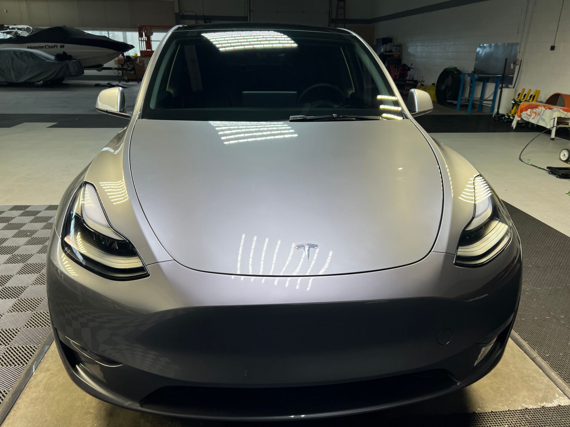 A gray tesla model y is parked in a garage