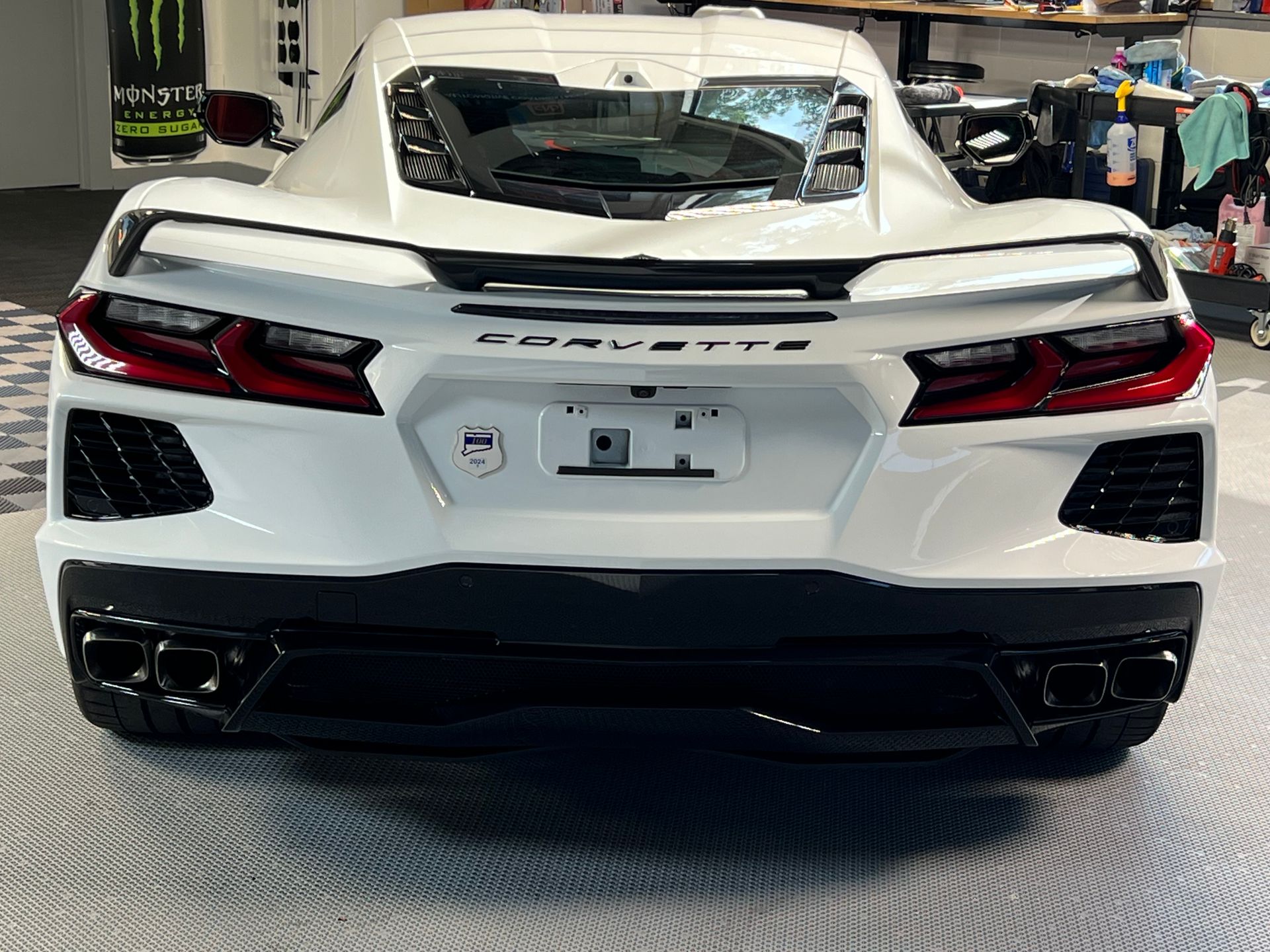 A white corvette is parked in a garage.