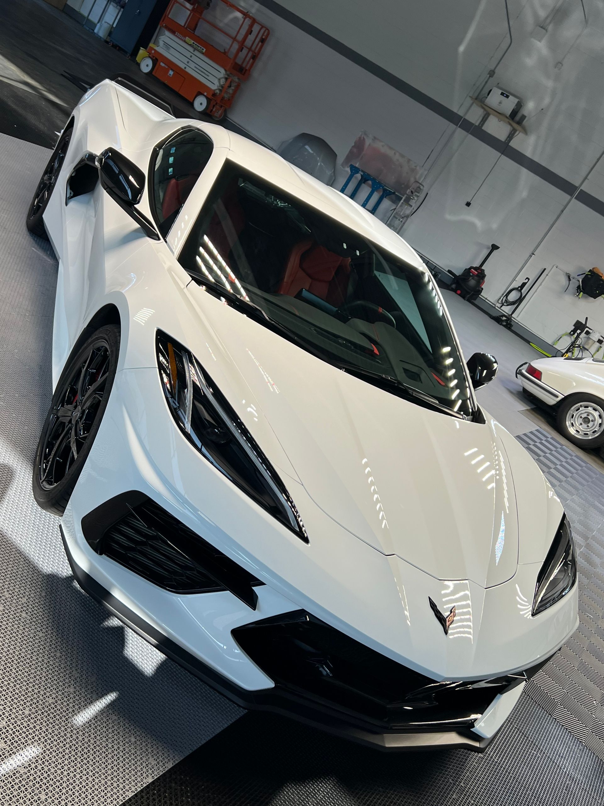 A white sports car is parked in a garage.