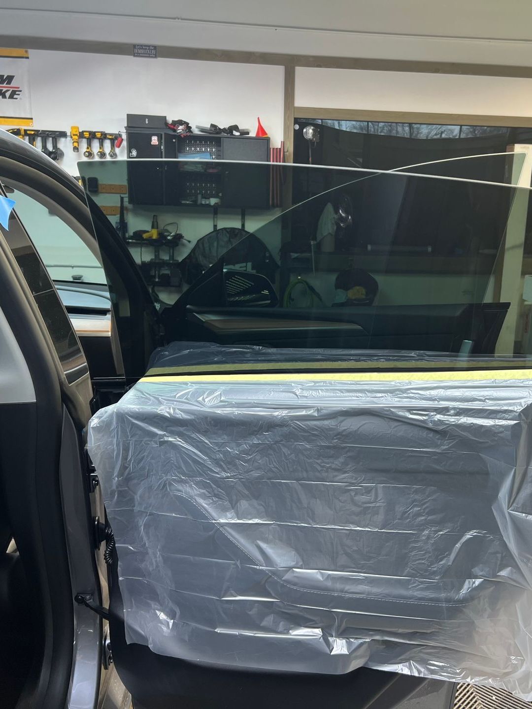 A car is covered in plastic wrap in a garage.