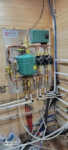 Basement furnace with metal ductwork and pipes beside a utility cabinet