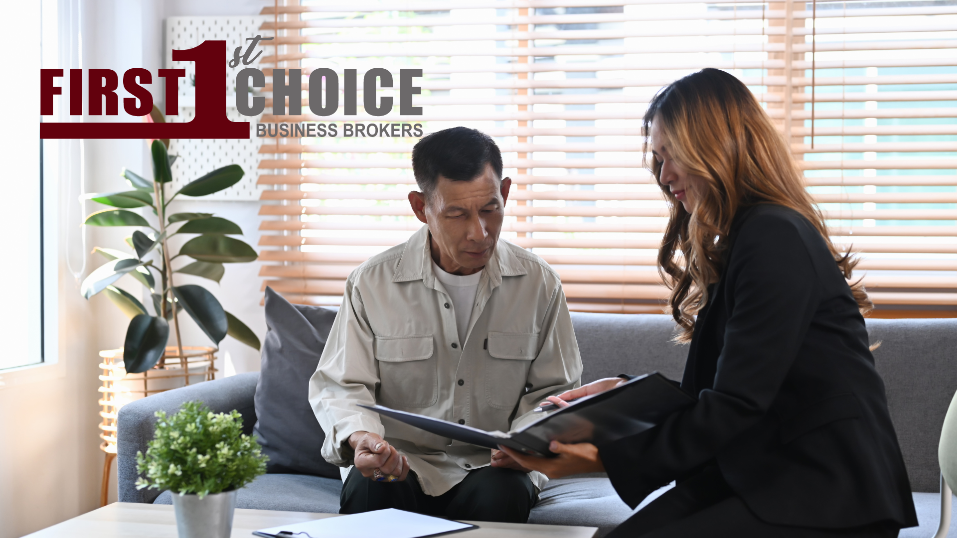 A man and a woman are sitting on a couch looking at a clipboard.