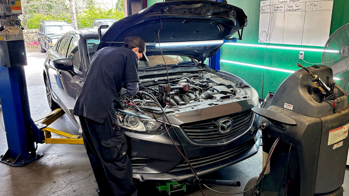 a mechanic is working on a car engine with a wrench .