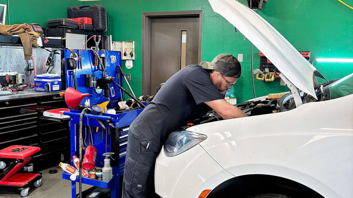 a mechanic is writing on a clipboard while working on a car .
