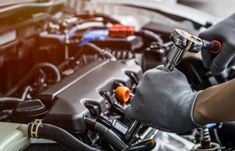 a mechanic is working on a car engine with a wrench .