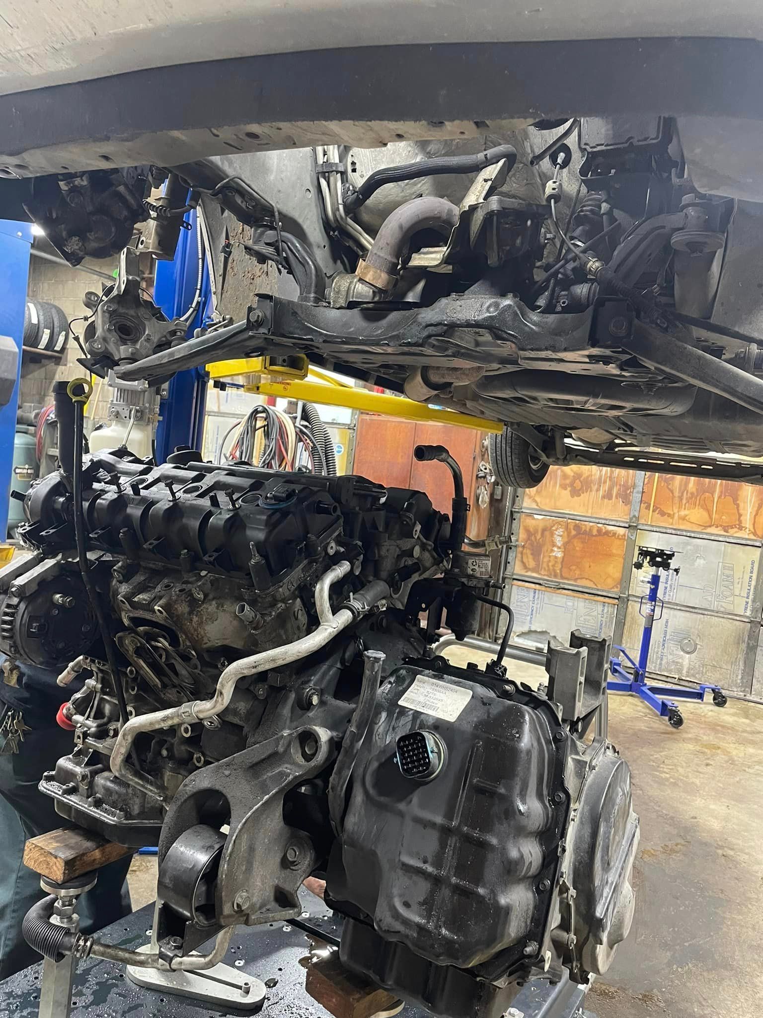 Damaged car engine removed in a garage, with charred parts and exposed undercarriage.