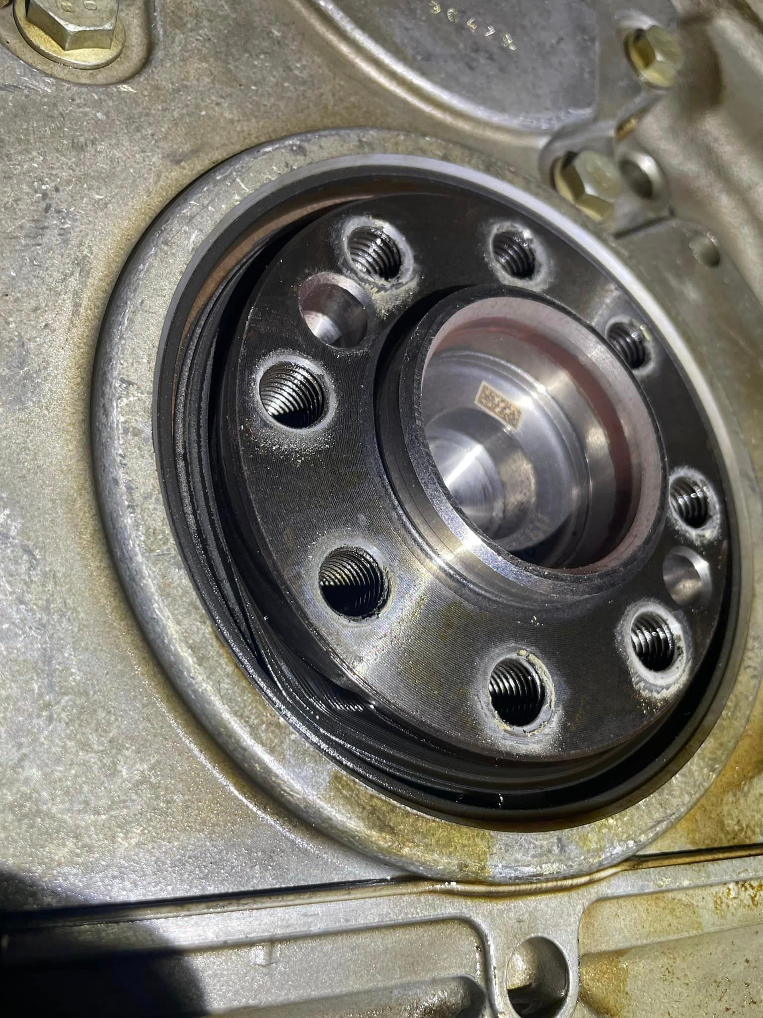 Close-up of a metal flange with a circular bearing or hub and multiple bolt holes on a machine casing