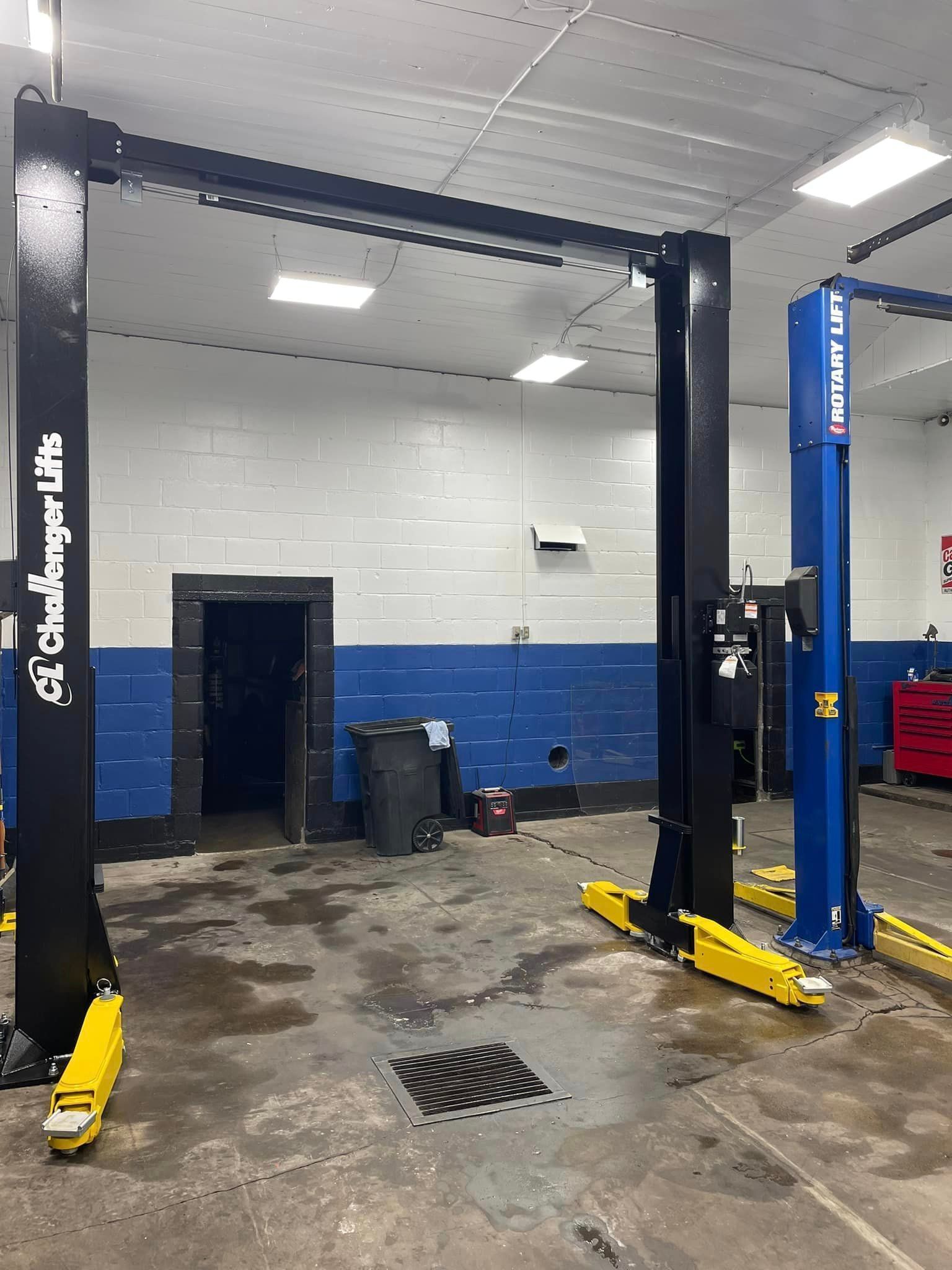 Auto repair shop with two black and blue car lifts in a wet garage bay