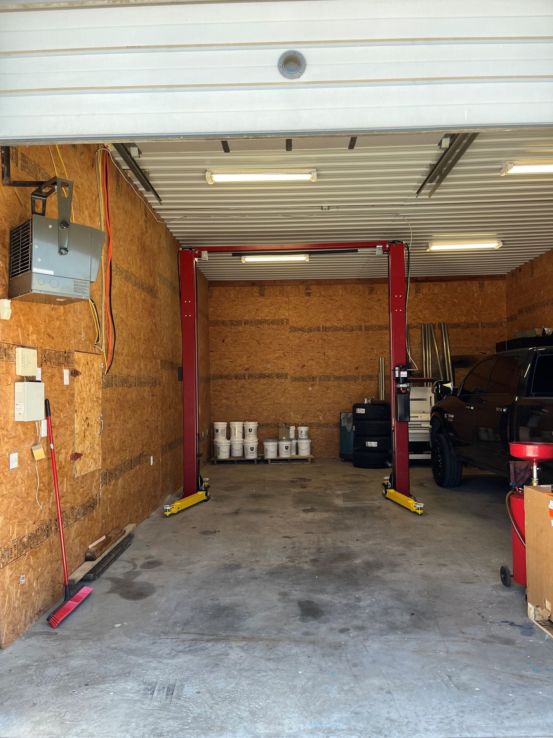 Empty storage garage with open bay door, red lift posts, and boxes along the walls