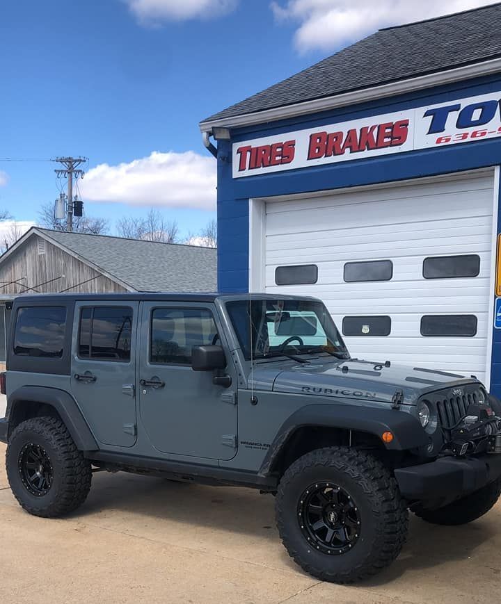 A jeep is parked in front of a tires and brakes store.
