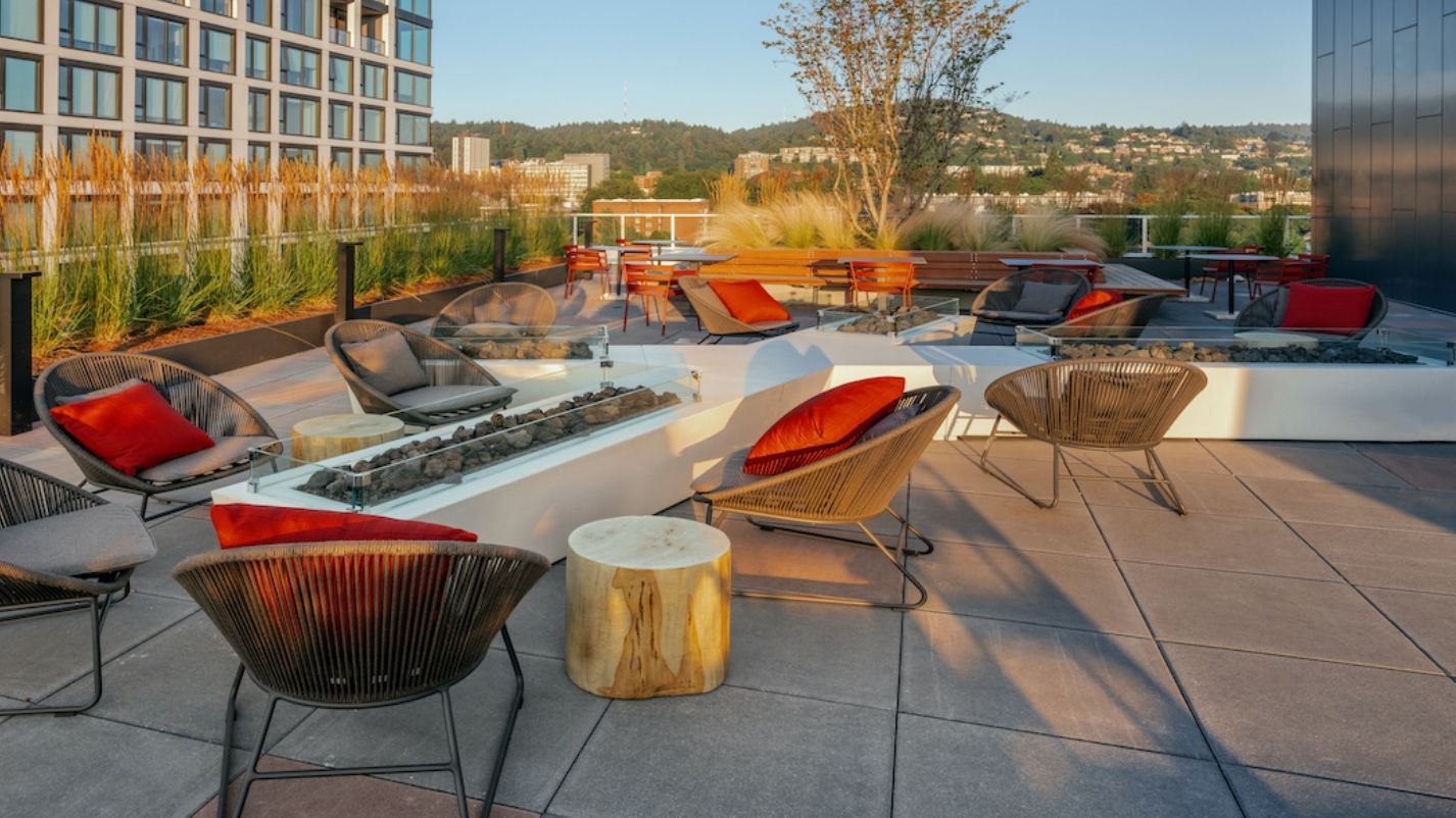 A patio with chairs , tables and a fire pit.